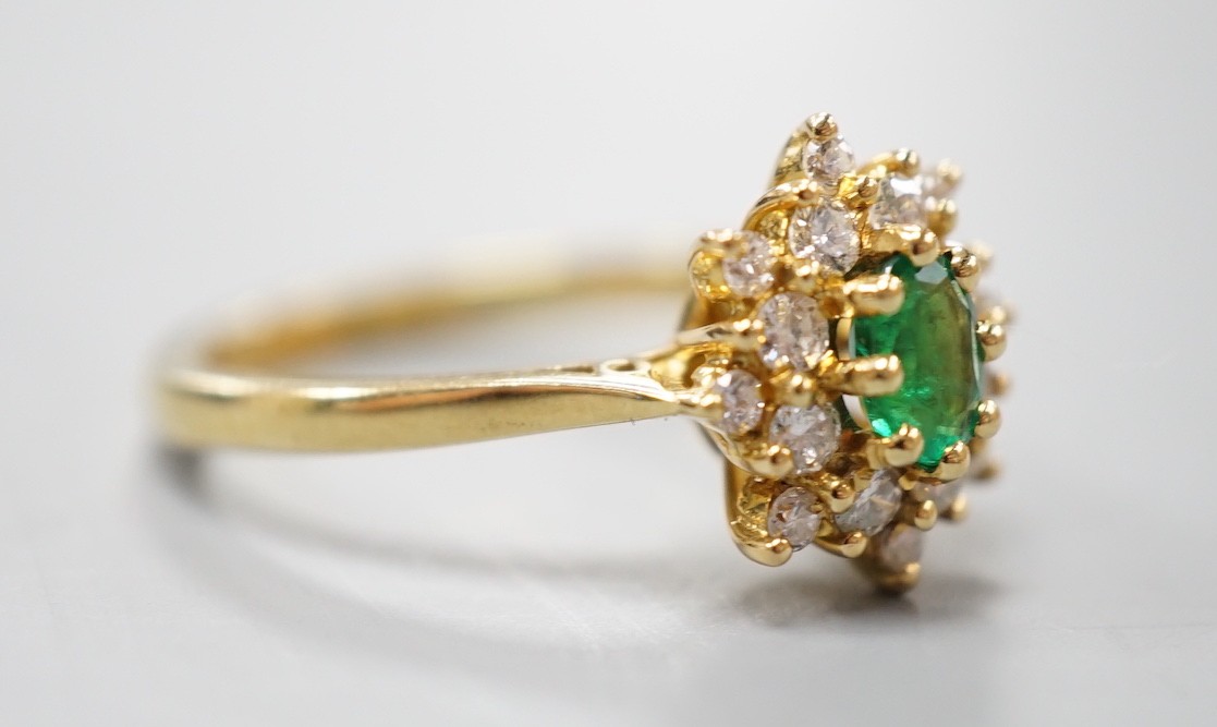 A modern 18ct gold, emerald and diamond set star shaped cluster ring, size L/M, gross weight 3.8 grams